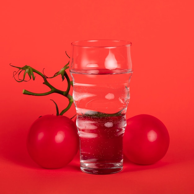 Verre d'eau entouré de tomates