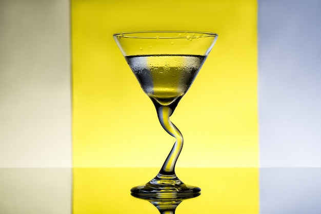 Verre avec de l'eau sur une surface grise et jaune