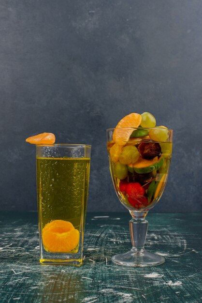 Verre de fruits mélangés et jus de mandarine sur table en marbre