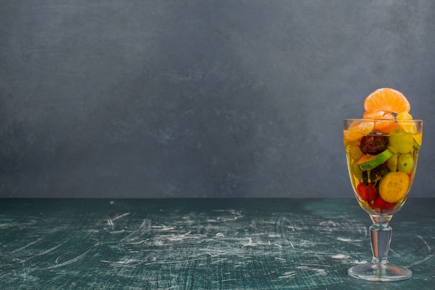 Verre de fruits mélangés sur table en marbre.