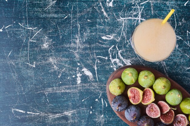 Un verre de jus aux figues vertes sur bleu.