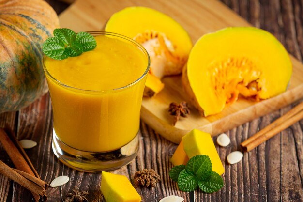 Un verre de jus de citrouille et de citrouilles crues hachées place sur un plancher en bois