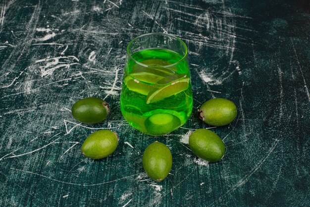 Photo gratuite verre de jus de feijoa et feijoas sur une surface en marbre.