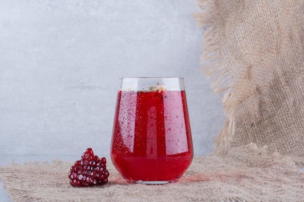 Un verre de jus de grenade sur de la toile de jute avec des graines.