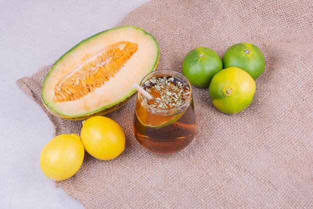 Un verre de jus avec des herbes et des fruits autour