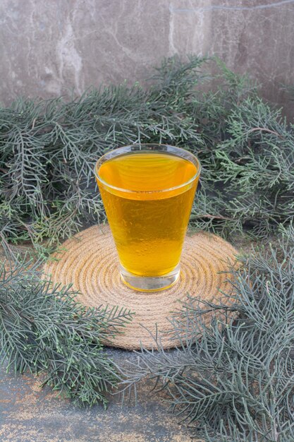 Un verre de jus jaune sur marbre.