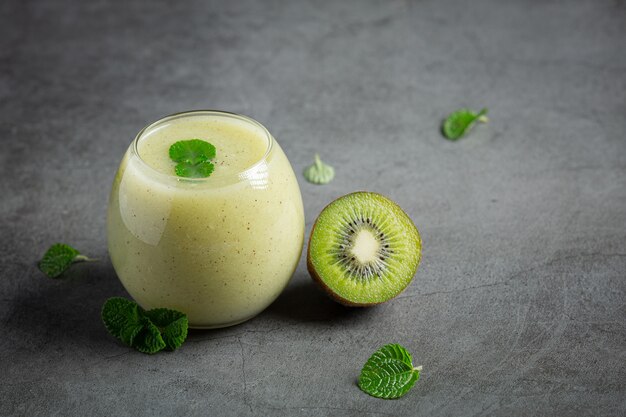 Verre de jus de kiwi posé sur un sol sombre