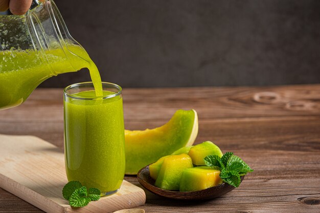 Verre de jus de melon posé sur un plancher en bois