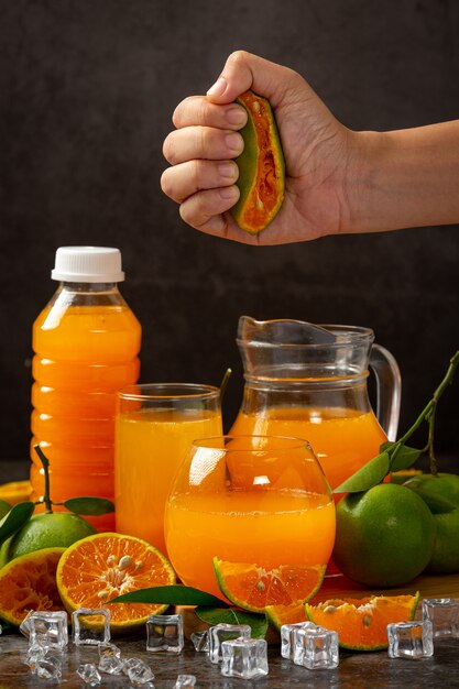 Un verre de jus d'orange et de fruits frais sur le sol avec des glaçons.