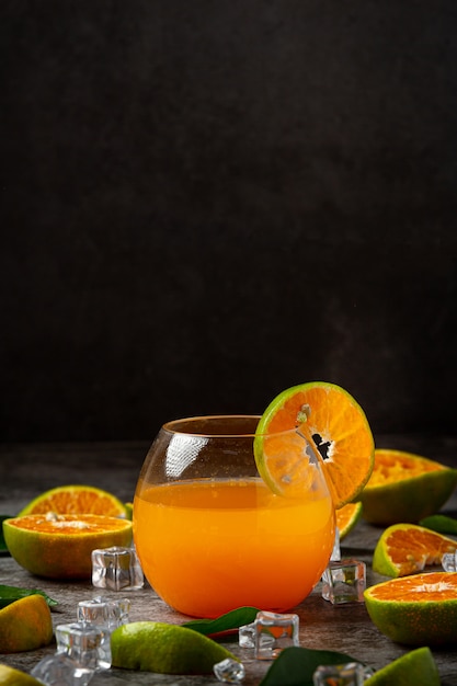 Un verre de jus d'orange et de fruits frais sur le sol avec des glaçons.