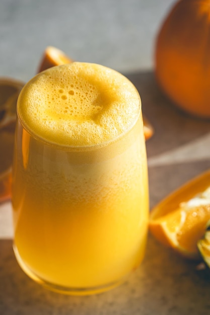 Un verre de jus d'orange en gros plan sur un fond flou avec des oranges