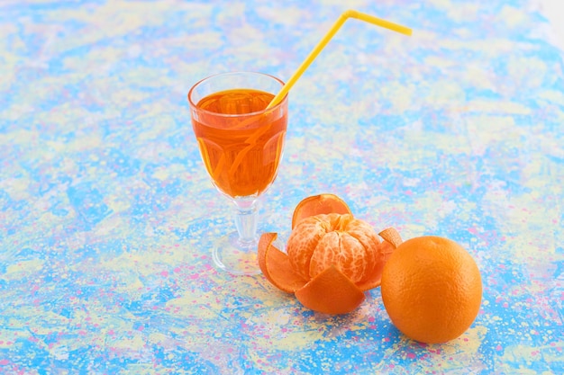 Un verre de jus d'orange avec des mandarines autour sur fond bleu. Photo de haute qualité