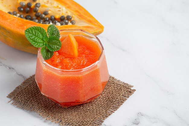 Verre de jus de papaye posé sur un sol en marbre blanc