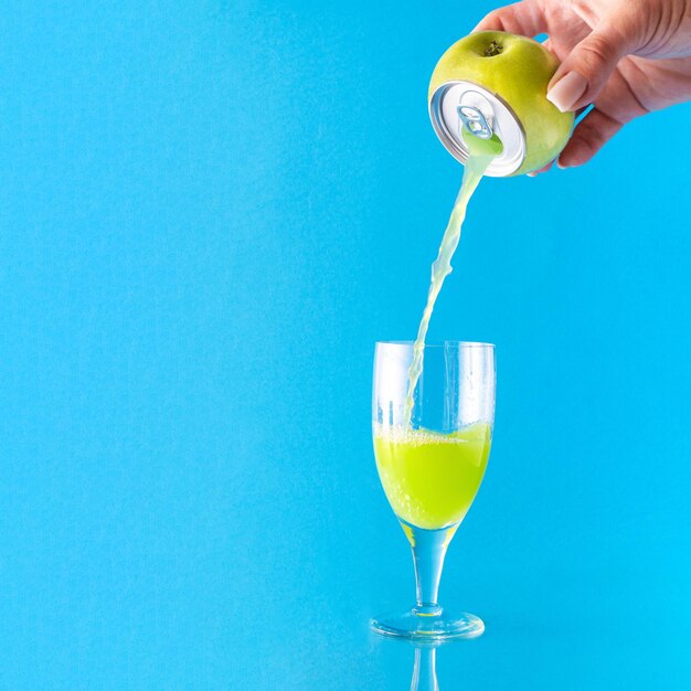 Verre de jus de pomme vert sain sur fond bleu pastel