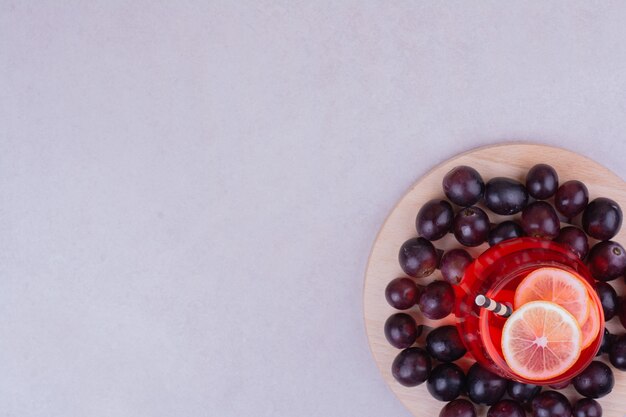 Un verre de jus rouge avec des baies de cerise sur une planche de bois