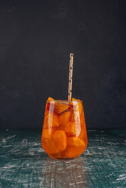 Verre de jus avec des tranches de coing et de la paille sur table en marbre