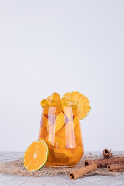 Un verre de jus avec des tranches de fruits et de la cannelle.