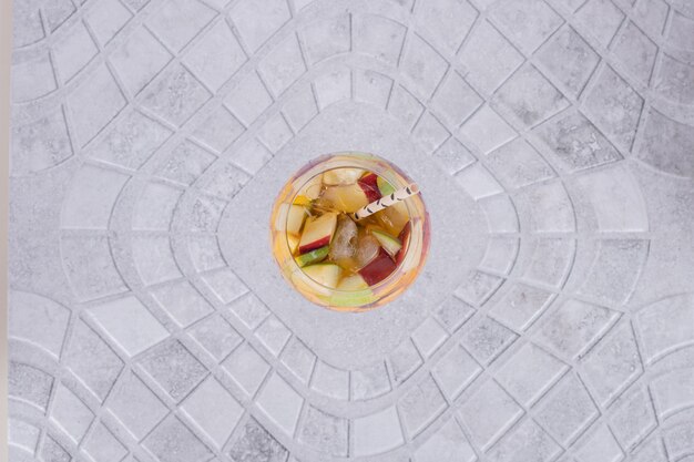 Un verre de jus avec des tranches de fruits sur une table en marbre.