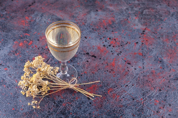 Verre de jus avec des tranches de poire et des fleurs séchées sur fond bleu.