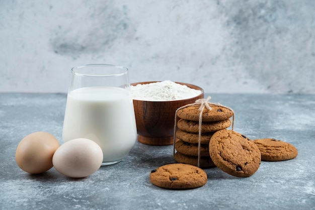 Un verre de lait chaud avec de délicieux biscuits sur une table grise.