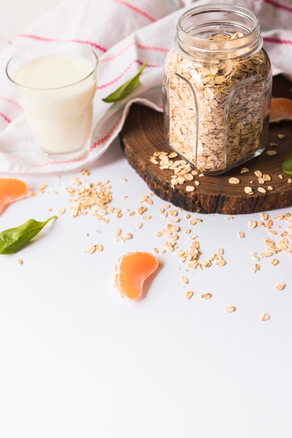 Un verre de lait; feuilles de basilic; L&#39;avoine; tranches d&#39;orange et serviette sur fond blanc