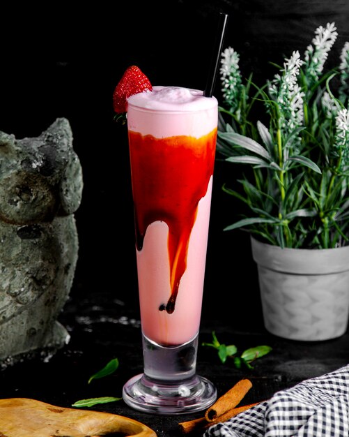 Un verre de lait frappé aux fraises garni de sirop de fraise