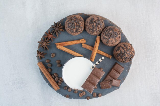 Verre de lait avec paille, chocolat et biscuits sur morceau de bois. photo de haute qualité