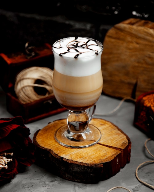 Un verre de latte chaud avec de la mousse sur un chanvre d'arbre