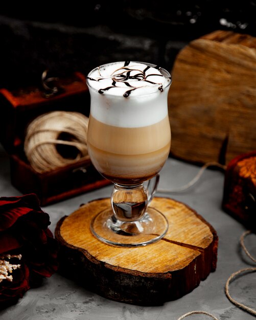 Un verre de latte chaud avec de la mousse sur un chanvre d'arbre