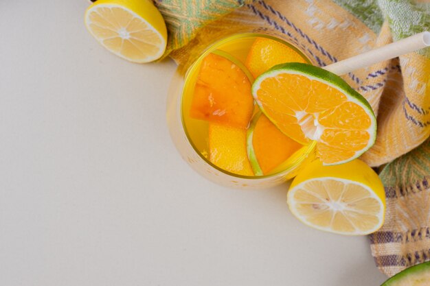 Un verre de limonade avec des tranches de citron sur une surface blanche.