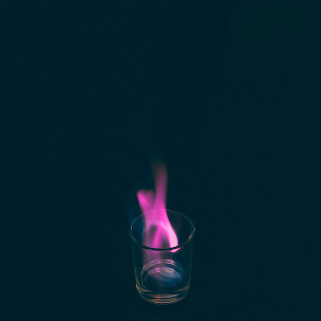 Photo gratuite verre à liqueur tequila brûlant avec flamme rose