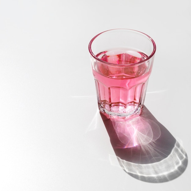 Photo gratuite verre liquide rouge avec une ombre sombre brillante sur fond blanc