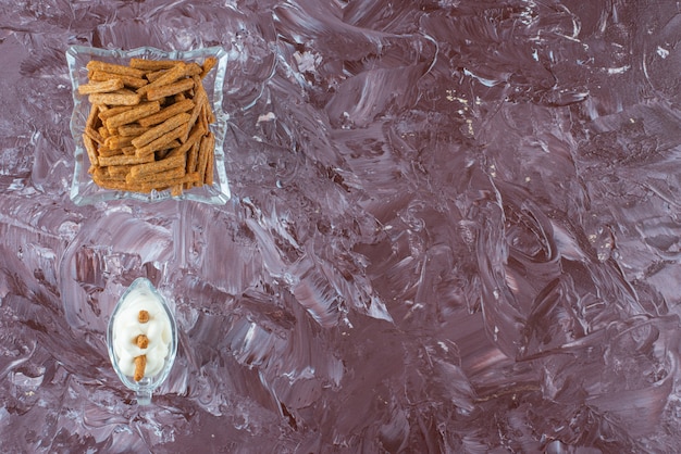 Un verre de mayonnaise et de chapelure croustillante dans un bol en verre, sur la table en marbre.