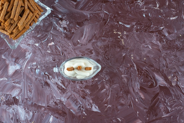 Un verre de mayonnaise et de chapelure croustillante dans un bol en verre, sur la table en marbre.