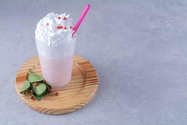 Un verre de milkshake à la crème sur une plaque en bois , sur le fond de marbre.