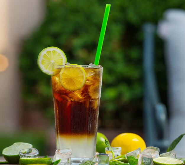 Un verre de mojito cocktail rouge avec une tranche de citron, citron vert sur un fond de restaurant - Image