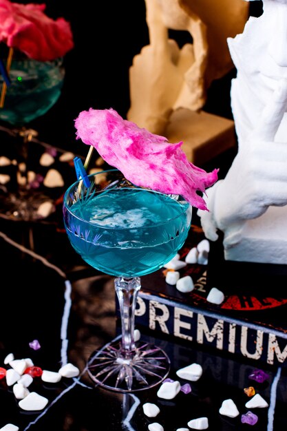 Un verre à pied long en cristal avec un lagon bleu garni de coton doux rose