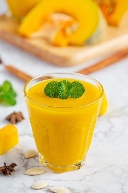 Un verre de place de jus de citrouille sur un sol en marbre blanc