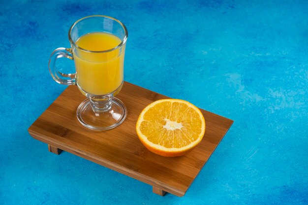 Un verre tasses de jus d'orange sur planche de bois.