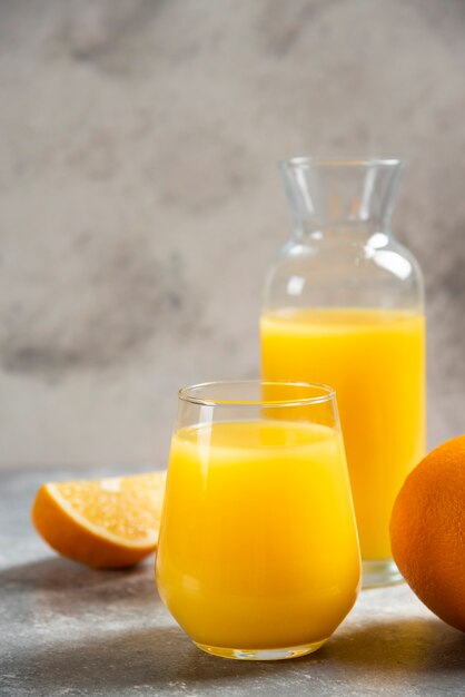 Un verre de tasses de jus d'orange et de tranches d'orange.