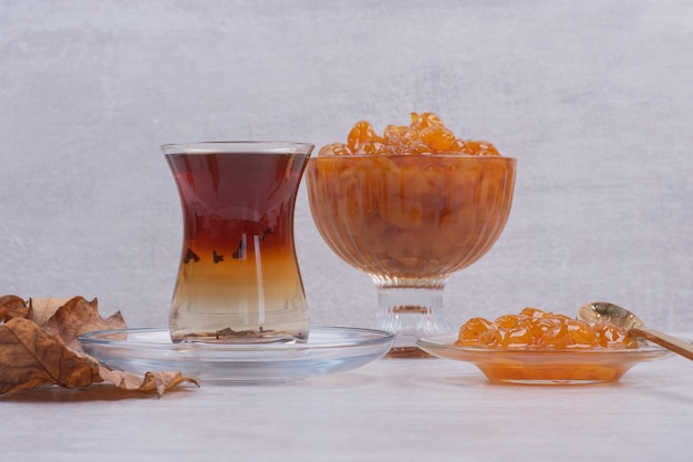 Verre de thé et confiture de baies sur blanc.