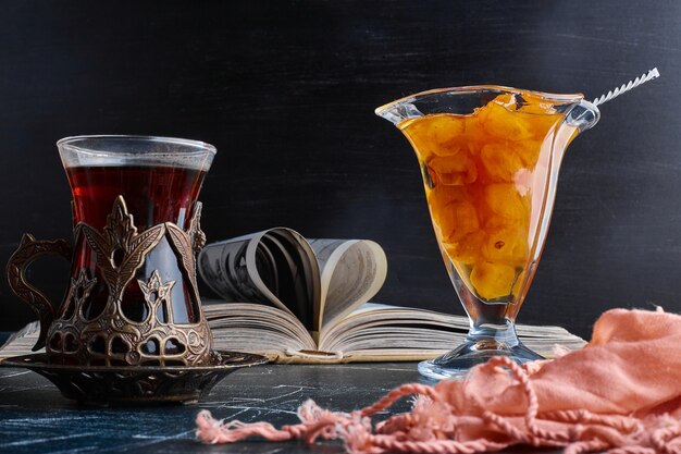 Un verre de thé avec une confiture de cerises.