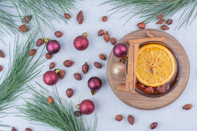 Verre de thé à l'églantier et boules de Noël sur la surface.