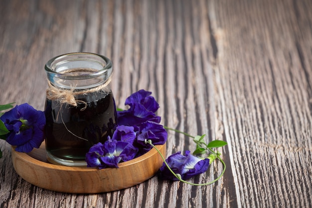 Verre de thé de fleur de pois papillon mis sur plateau en bois