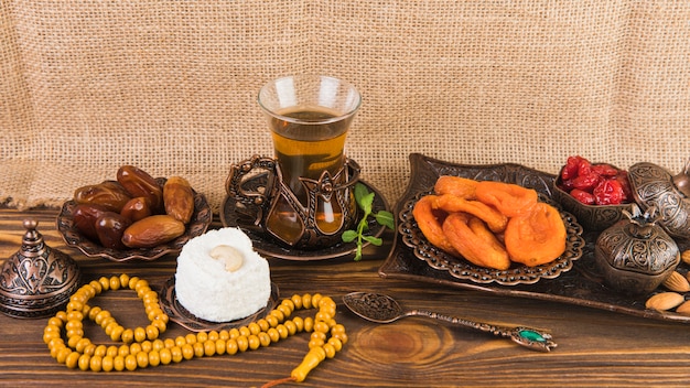 Photo gratuite verre à thé avec des fruits secs et des perles sur une table en bois