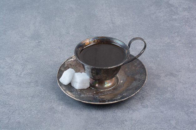 Un verre de thé noir arôme sur table grise.