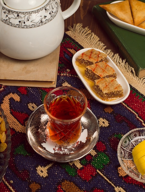 Un verre de thé traditionnel armudu avec des bonbons et sheki pakhlavasi sur dark