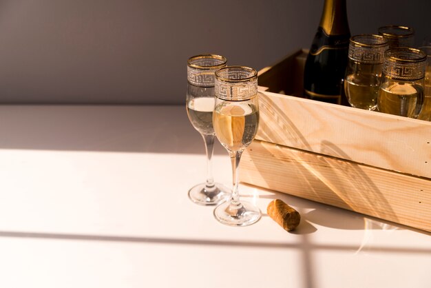 Verre de vin et champagne dans une caisse en bois sur une table blanche