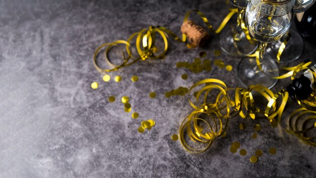 Verre à vin avec des confettis dorés décoratifs et des banderoles sur une surface en béton