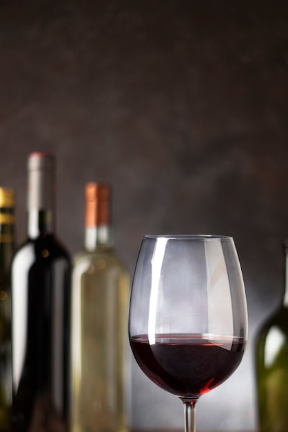 Verre à vin rouge gros plan avec des bouteilles derrière